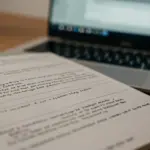 Script page with revisions and a laptop, symbolizing the rewriting process in mini-series production.